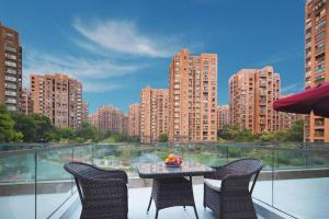 a table and chairs on a balcony with a view of a city at Vienna Hotel Hangzhou Jiubao Sijiqing Suanli Town in Hangzhou