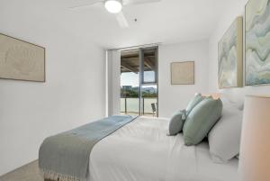 a white bedroom with a large bed and a window at Cairns Coastal Charmer - Your Waterfront Sanctuary in Cairns +31 photos