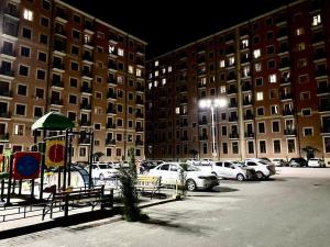 a parking lot with cars parked in front of tall buildings at Luxanda Plaza in Samarkand