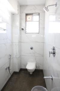 a white bathroom with a toilet and a window at Vasantharaja Inn in Puducherry