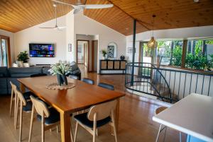 a dining room and living room with a wooden table and chairs at Wave Hill and The Pool House in Lennox Head