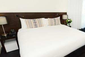 una camera da letto con un grande letto bianco con due lampade di Oaks Gladstone Grand Hotel a Gladstone