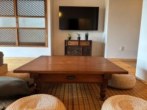 a living room with a wooden table and a flat screen tv at 真鶴海の見える古民家風ジャパニーズルームapartment Hotel途乃中W2 in Manazuru +14 photos