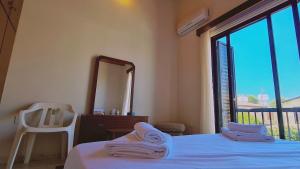 ein Schlafzimmer mit einem Bett, einem Spiegel und einem Stuhl in der Unterkunft STAY Sea Gem Apartment in Meneou