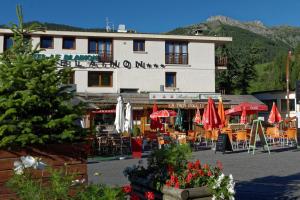a building with tables and umbrellas in front of it at Hôtel Le Blainon in Auron