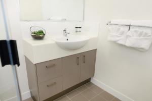 a white bathroom with a sink and towels at Oaks Middlemount Suites in Middlemount