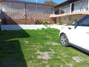a white car parked in the grass in a yard at Departamentos y tinajas Blanquita mahuida in El Quisco