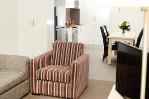 sala de estar con silla y cocina en Oaks Moranbah Suites, en Moranbah