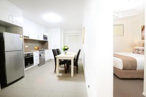 een keuken en een slaapkamer met een bed en een tafel bij Oaks Moranbah Suites in Moranbah