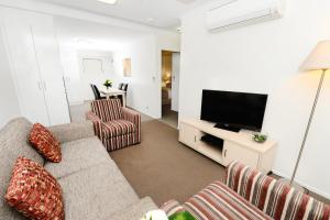 een woonkamer met een bank en een flatscreen-tv bij Oaks Moranbah Suites in Moranbah