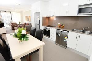 a kitchen with a table and a refrigerator at Oaks Moranbah Suites in Moranbah