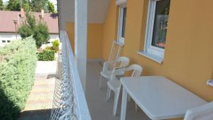 a balcony with a white table and white chairs at Ilona Vendégház in Siófok