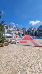a large red ramp next to a pool with buildings at Penthaus Cacao Beach in Sunny Beach