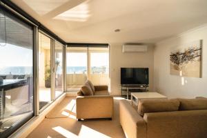 a living room with a couch and a flat screen tv at Beach View Apartment in Cottesloe in Perth