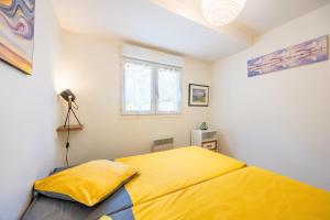 a yellow bed in a white room with a window at Gîte Du Peintre in Challans