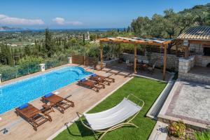 a backyard with a swimming pool with chairs and a table at Villa Clairy in Mouzákion