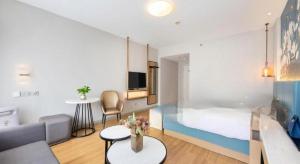 a room with a bed and a couch and a table at Jinjiang Inn Jinhua Binhong Road in Jinhua