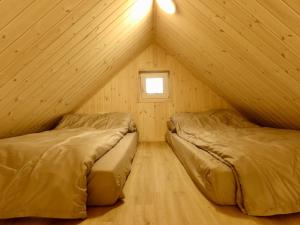 two beds in a room with a roof at Gray House in Marijampolė