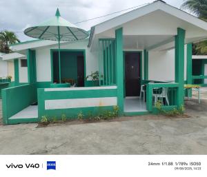a green and white house with an umbrella at Marilou Guesthouse in Bantayan Island