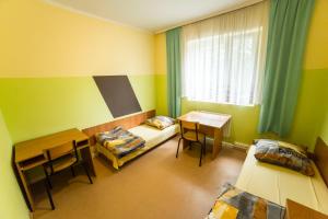 Cette chambre comprend deux lits, une table et un bureau. dans l'établissement Ondraszka, à Katowice