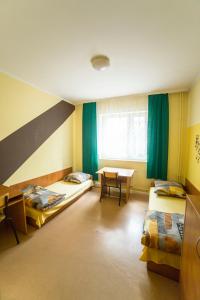Cette chambre comprend 2 lits et une table. dans l'établissement Ondraszka, à Katowice