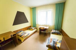 een kamer met 2 bedden, een tafel en een raam bij Ondraszka in Katowice