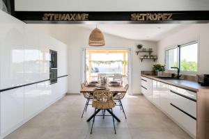 a kitchen with white cabinets and a table with chairs at Splendid villa with swimming pool & sea view in Saint-Peïre-sur-Mer