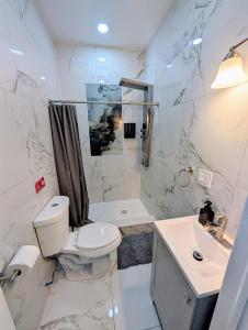 a white bathroom with a toilet and a sink at Newly Renovated 2B 2BA apt! mins to PATH & NY! in Jersey City +9 photos