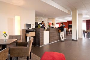 a lobby with a bar with people standing at a counter at Hotel Sachsen-Anhalt in Barleben