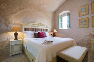 a bedroom with a large white bed and a window at The Old Markets in Symi