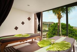 a room with two beds and a balcony with a palm tree at Grandmas Plus Hotel Seminyak in Seminyak