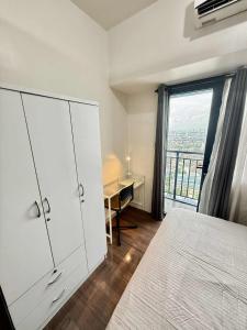 a bedroom with a bed and a desk and a window at Makati One Bed Room with Balcony Air Residence SMDC in Sampong