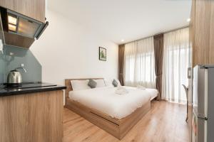 a bedroom with a bed and a kitchen with a refrigerator at Daisy House Near Bui Vien - Self Checkin in Ho Chi Minh City