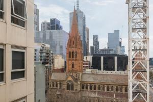 a tall church steeple in a city with buildings at City center apartment with a view in Melbourne