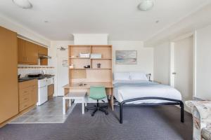 a bedroom with a bed and a desk and a green chair at City center apartment with a view in Melbourne