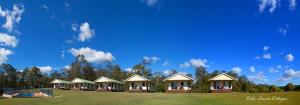 a row of cottages on a field with a blue sky at Lake Barra Cottages in Downsfield