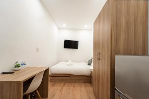 a bedroom with a bed and a desk and a tv at Daisy House Near Bui Vien - Self Checkin in Ho Chi Minh City