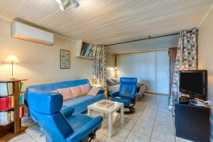 a living room with a blue couch and chairs and a tv at Location Fontaine de Sarac in Clermont-lʼHérault