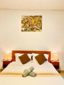 a bedroom with a bed with two lamps and a painting on the wall at The Angga House in Bangli