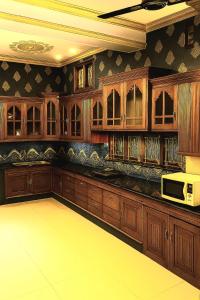 a large kitchen with wooden cabinets and a microwave at SP Home in Trivandrum