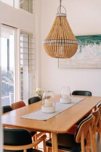 a dining room with a wooden table and a chandelier at Pool House, luxury 2 bedroom with ocean views, pool and sauna in Lennox Head