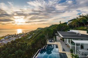 a house with a swimming pool next to the ocean at Pool House, luxury 2 bedroom with ocean views, pool and sauna in Lennox Head