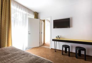 a bedroom with a bed and a desk and a tv at Viešbutis Simpatija in Druskininkai
