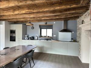 a kitchen with white cabinets and a wooden ceiling at SCI Maison Rouge 1 in Bonnac-la-Côte