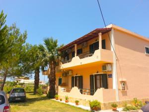 a yellow house with cars parked in front of it at Feakes Apartments in Arillas