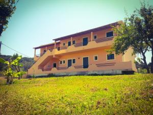 ein Gebäude auf einem Hügel mit einem grünen Feld in der Unterkunft Feakes Apartments in Arillas