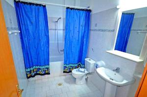 een badkamer met blauwe gordijnen, een toilet en een wastafel bij Nitsa's Apartments in Megálon Choríon