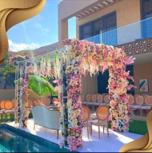 an arch covered in flowers next to a swimming pool at Nameer bay in Bandar Jişşah