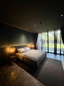 a bedroom with a bed and a large window at inchantreemeedao in Ban Chuk Kum