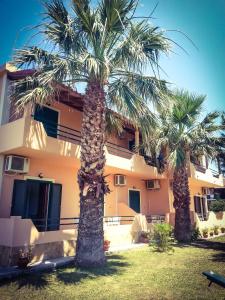 two palm trees in front of a building at Feakes Apartments in Arillas